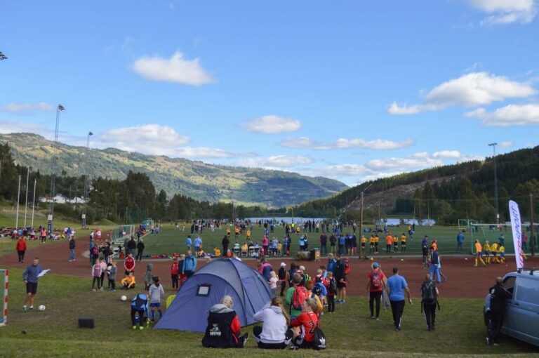 Gruppe menneske framfor telt og fotballbane